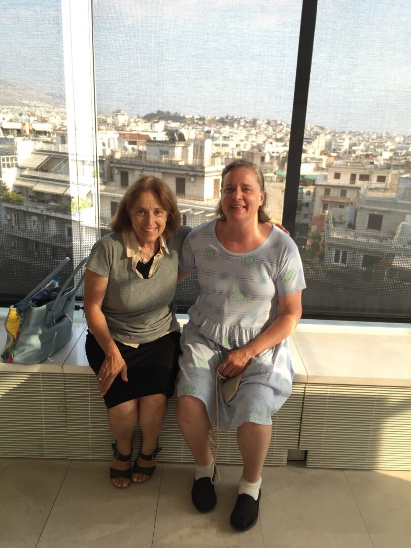 Two women sitting on a window sill.