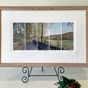 A framed print of a road with trees in the background.