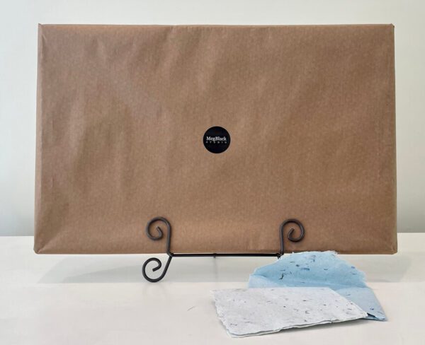 A brown box with a blue cloth on top of SOLD. June, River Road, in a red wooden frame, 35.5 x 17.5 x 1 inches.