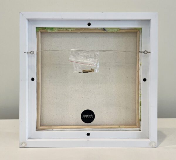 A white frame with a piece of paper in it.