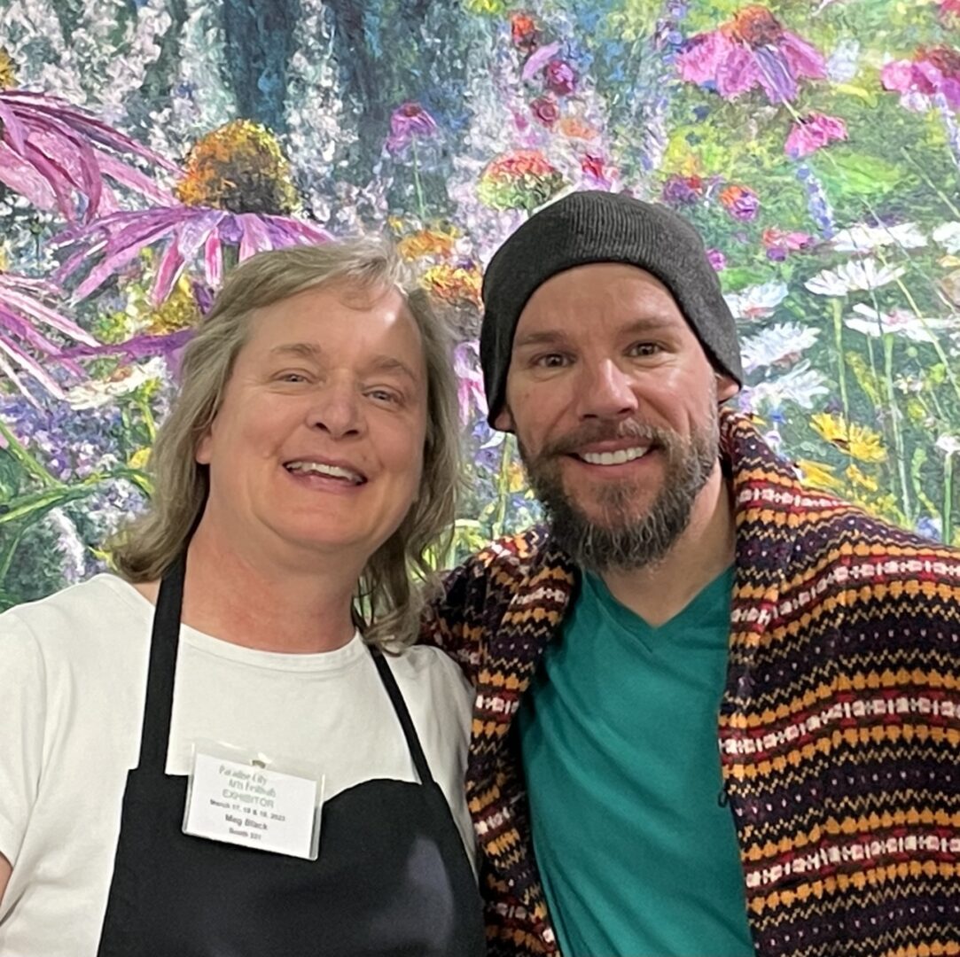 A man and woman standing in front of a mural of flowers.