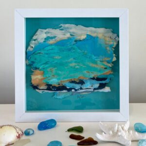 A framed piece of art with sea shells and sand.