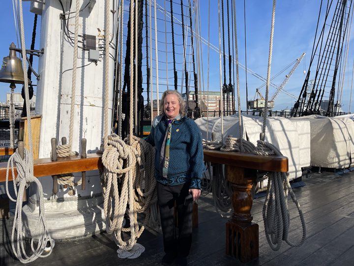 A woman standing on the deck of a tall ship.