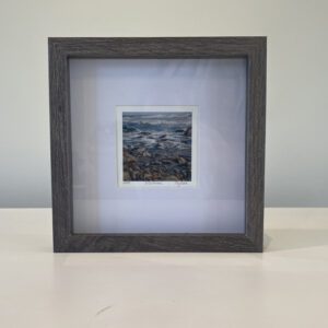 A black frame with a photo of a rocky beach.