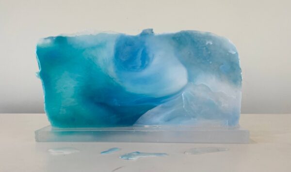 A translucent blue and white soap bar with swirls, displayed on a white surface with droplets visible.